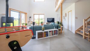 Un salon moderne avec une table de baby-foot, une bibliothèque, un téléviseur et une cheminée.