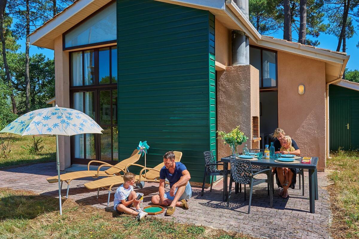 Une maison moderne dotée d’un patio. On y trouve une table avec des chaises, une table à manger et un enfant qui joue avec un jouet.