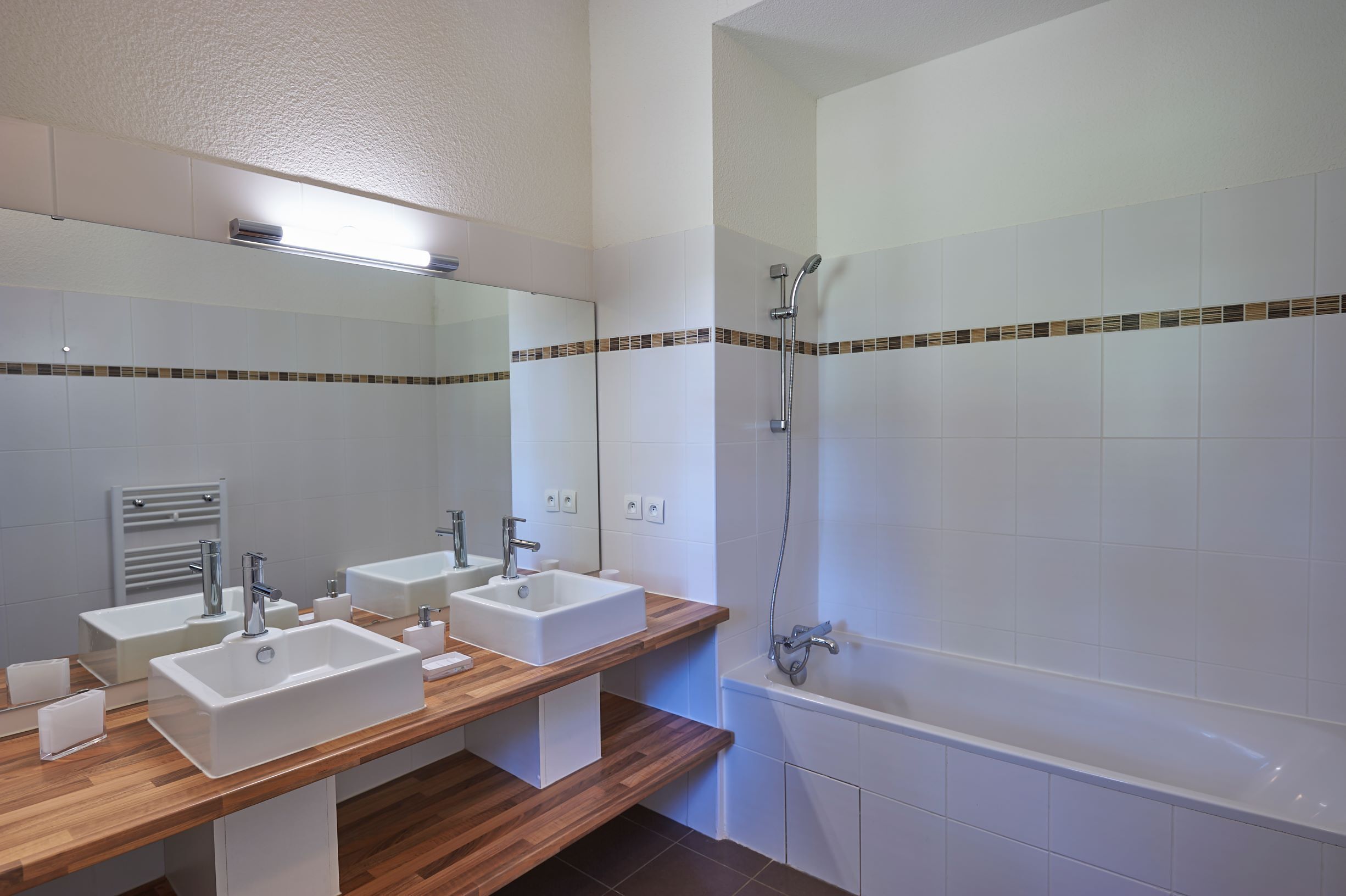 A modern bathroom with two sinks, a mirror, a shower, and a bathtub.
