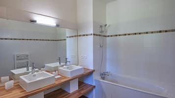 A modern bathroom with two sinks, a mirror, a shower, and a bathtub.