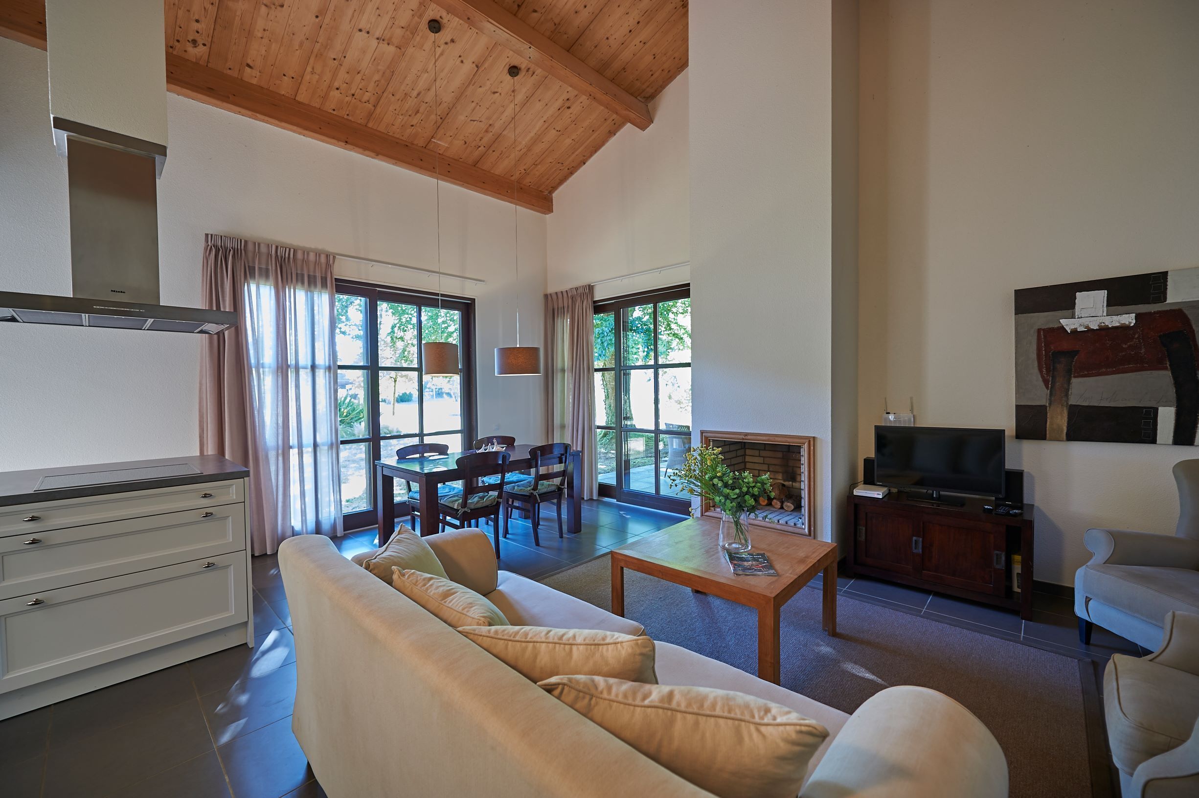 A spacious living area with a high ceiling, a dining table, and a sofa.