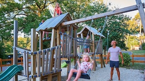 A playground with a wooden play structure, including a slide and swings. - FranceComfort - Château de Salles (Salles)