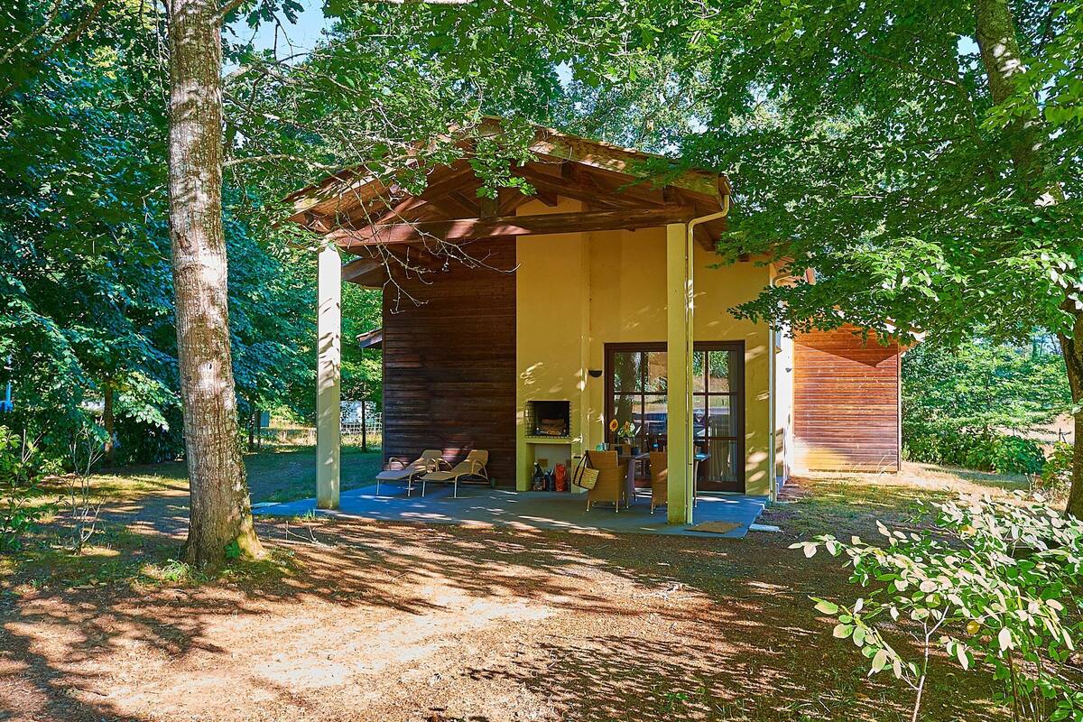 Un chalet rustique avec une façade en bois, une véranda et un petit espace extérieur aménagé pour s’asseoir.