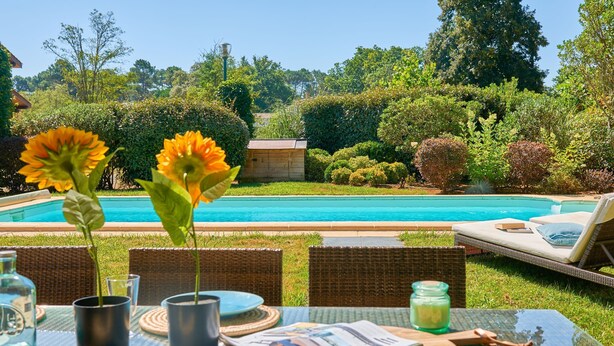 A poolside setting with a table set for two, a wooden deck, and a view of a swimming pool. - FranceComfort - Château de Salles (Salles)
