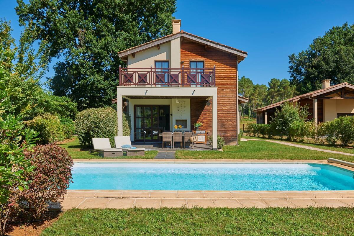 Une maison à deux étages dotée d’un balcon, d’une piscine et d’un jardin bien entretenu.