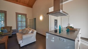 A modern living room with a sofa and a dining table, a kitchen with a built-in island, and a large window with curtains. - FranceComfort - Château de Salles (Salles)