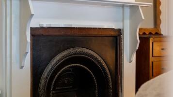 A fireplace with a white mantel, a framed abstract painting above it, and a wooden cabinet to the right.
