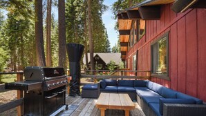 A deck with a grill, a wooden table, and blue outdoor seating. - Modern Retreat Near Dog-Friendly Beach & Eateries (Carnelian Bay)