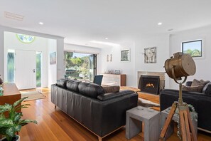 Un salon moderne avec une cheminée, des canapés en cuir et un lampadaire sur trépied.