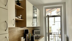 A modern kitchen with white cabinets, a wooden countertop, and a built-in oven. There is a window with a view of the outside. - 90 m2 - Space to Chill & Work & Rest (München)