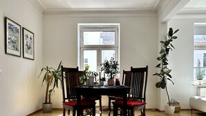 A dining area with a wooden table and chairs, a hanging light fixture, and potted plants. - 90 m2 - Space to Chill & Work & Rest (München)