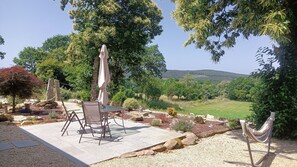 An outdoor patio with a table and chairs, surrounded by rocks and plants, overlooking a scenic landscape. - La Casita a haven of peace to escape and relax, close to cities and beaches. (Lugo Galicia)