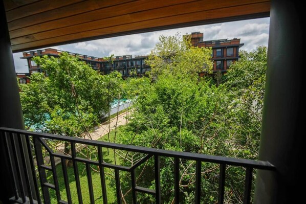 A balcony with a view of a building complex, trees, and a swimming pool. - Covanro Sigiriya - Brand New Luxury Hotel (Avudangawa)