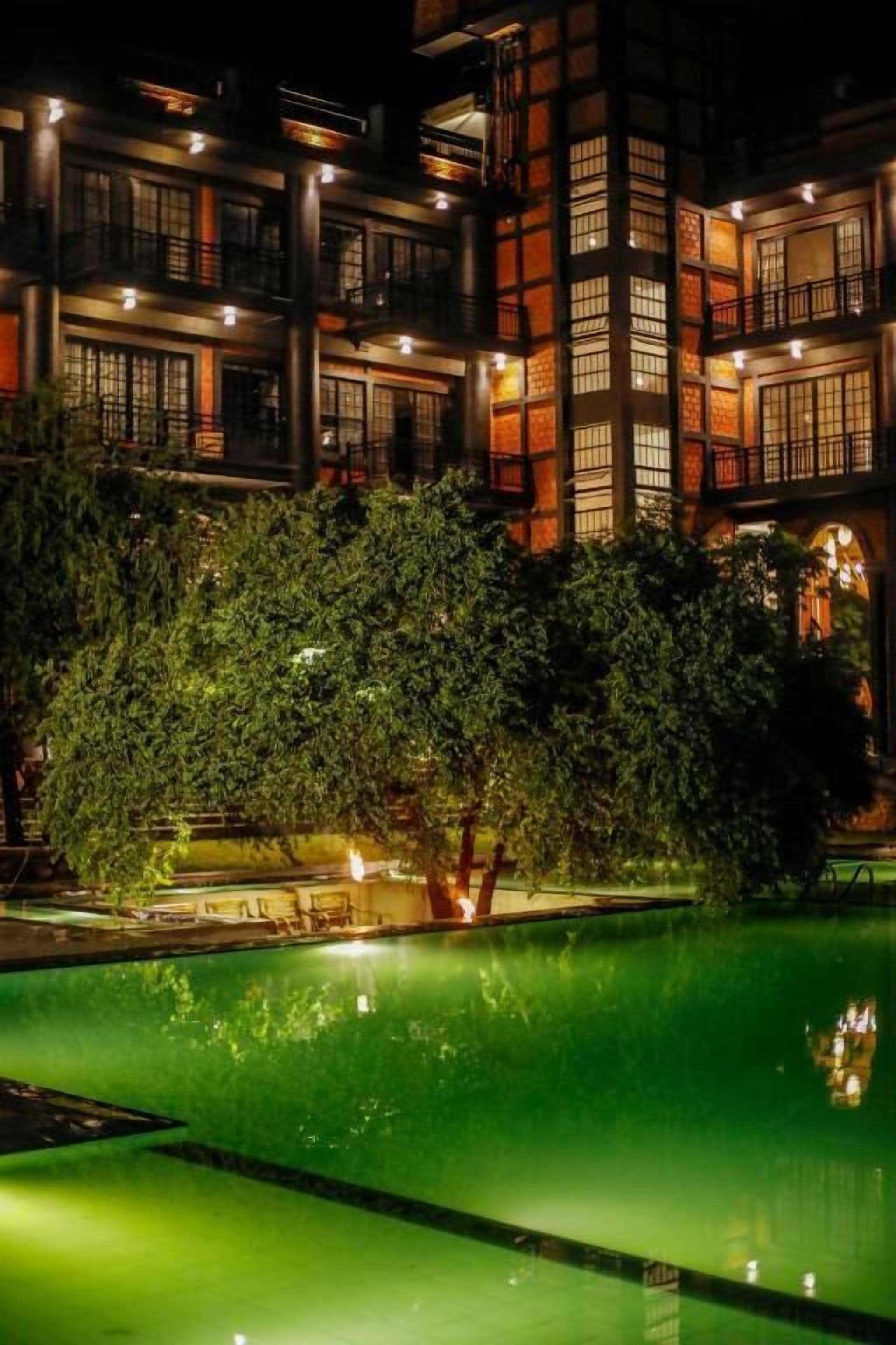 A multi-story building with a pool and trees in the foreground.