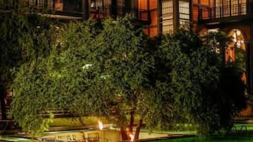 A multi-story building with a pool and trees in the foreground.