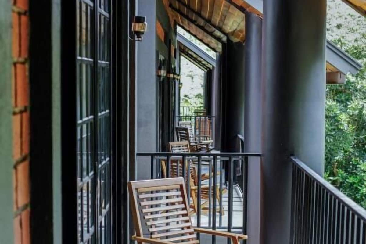 Un balcón con sillas de madera, baranda y vistas al exterior.