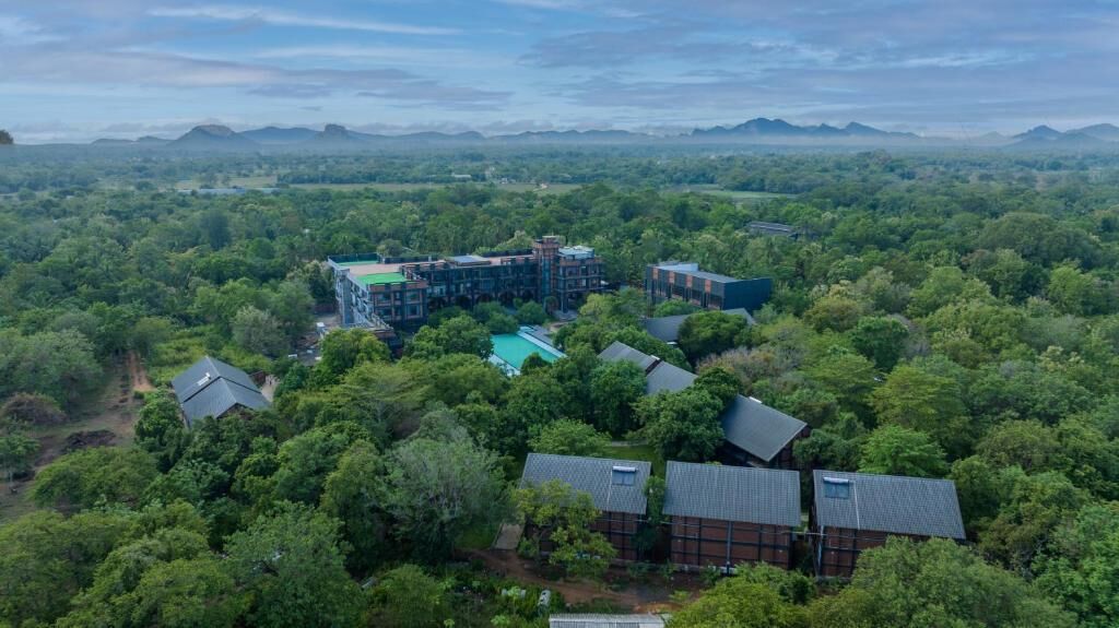 Vista aérea de un complejo turístico con varias edificaciones rodeado de un bosque denso.