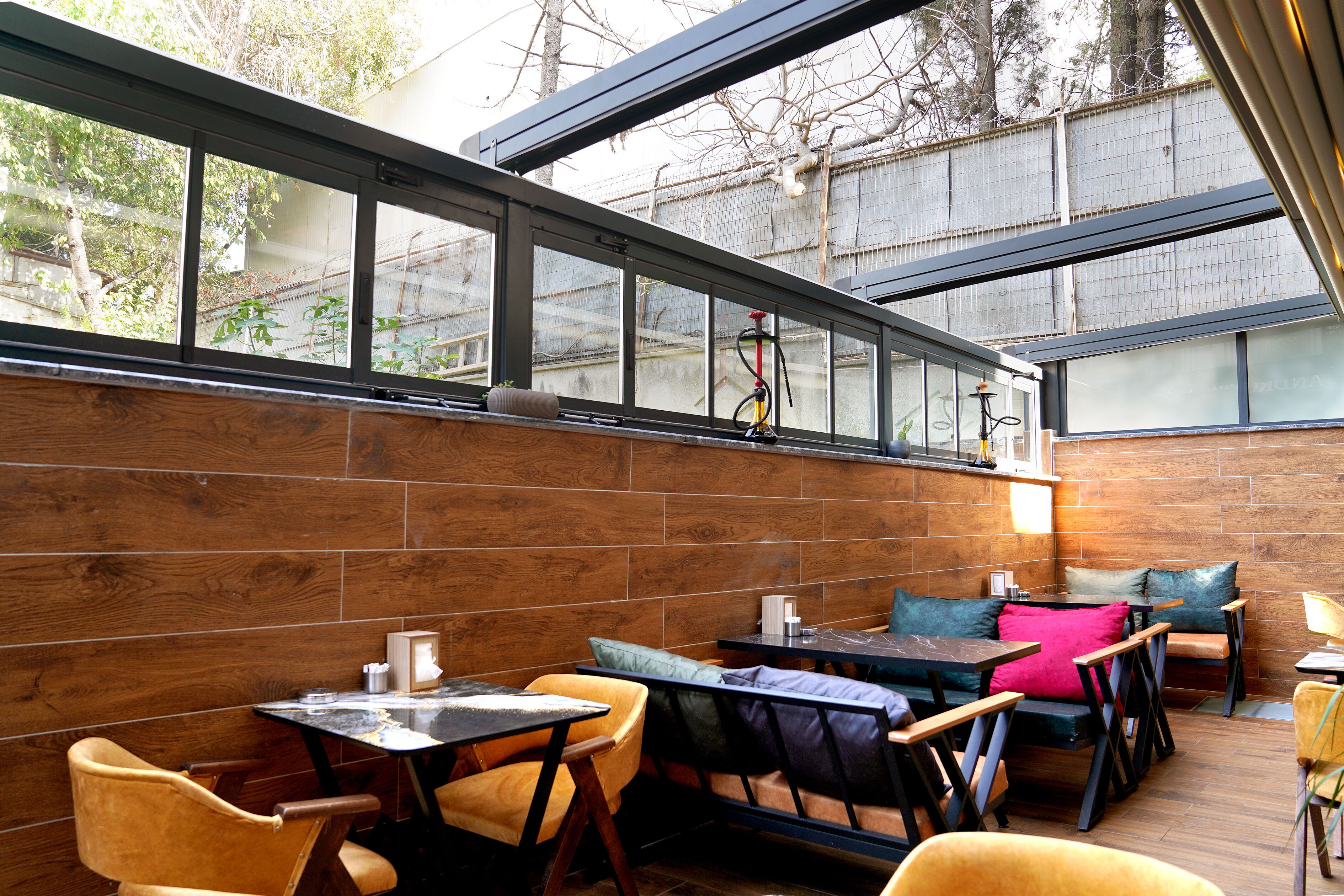 A restaurant with wooden walls, large windows, and a variety of seating including tables and chairs.