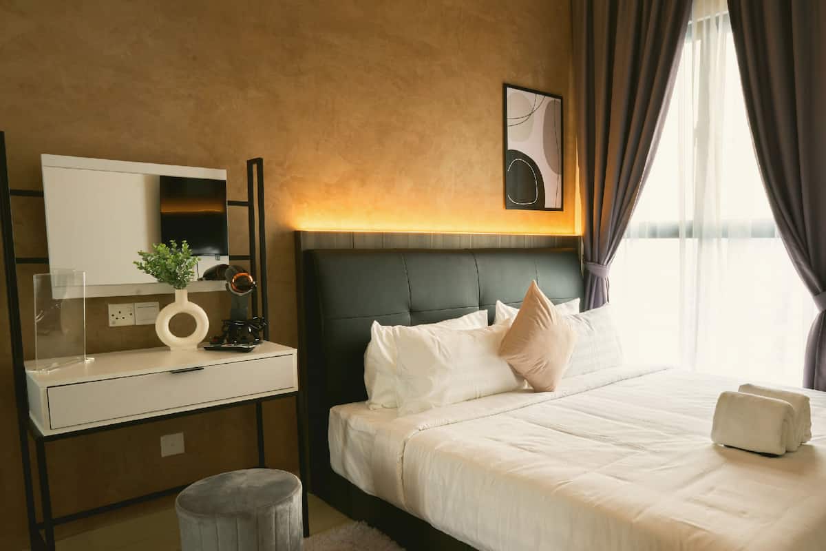 Ein Hotelzimmer mit Bett, Schreibtisch, Spiegel, Pflanze und einem Bild an der Wand.