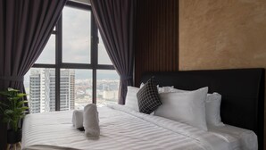 Une chambre d’hôtel avec un grand lit, une vue sur la ville par la fenêtre et une plante en pot.