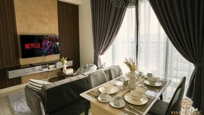 Un salon moderne doté d’un téléviseur à écran plat diffusant Netflix, d’un coin repas avec une table dressée pour quatre personnes et d’un canapé.