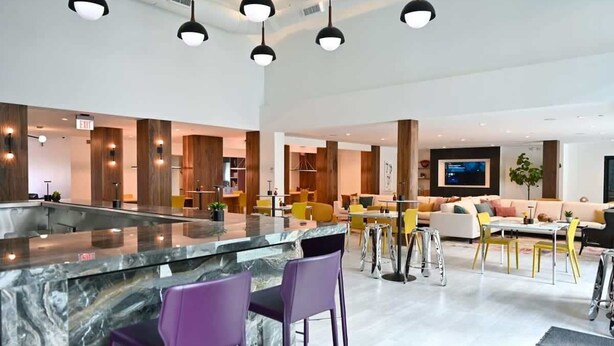 A modern kitchen with a marble island, purple bar stools, and pendant lighting. - Montrose Spring - Stylish 1 BR in Houston (Houston)