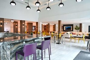 Uma cozinha moderna com ilha de mármore, banquetas roxas e iluminação pendente.