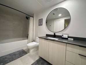 Bathroom features a bathtub, toilet, sink, and mirror.