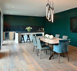Enjoy meals in the spacious kitchen and dining area with a large wooden table and pendant light.