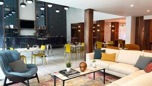 A modern hotel lobby with a dining area, a sofa, and a bar. - Montrose Spring - Stylish 1 BR in Houston (Houston)