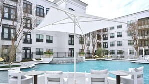 A modern hotel with a swimming pool, white outdoor furniture, and a covered seating area. - Montrose Spring - Stylish 1 BR in Houston (Houston)