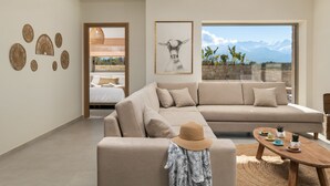 A modern living room with a beige sofa, a wooden coffee table, and a large window with a mountain view. - Sohora Estate up to 14 persons (Chania)