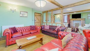 Ein geräumiges Wohnzimmer mit roten Ledersofas, einem Holztisch und einem Kamin.