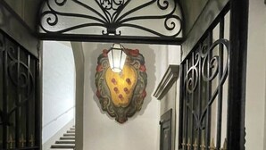A hallway with a wrought iron gate, a staircase, and a decorative wall piece.