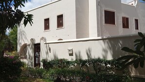 A white building with multiple windows and a door, surrounded by greenery and a clear sky. - Spacious Villa on Malindi Beach with pool and restaurant next to Golf course (Malindi)