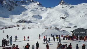 A ski resort with a large crowd, ski lifts, and a building labeled "Aulian Express".