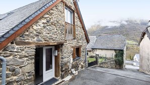 A stone building with a sloped roof and a small balcony.