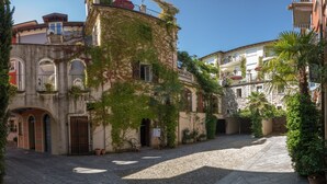 A cobblestone courtyard with buildings featuring arched doorways and balconies. - Residenza dei Fiori (Cannero Riviera)