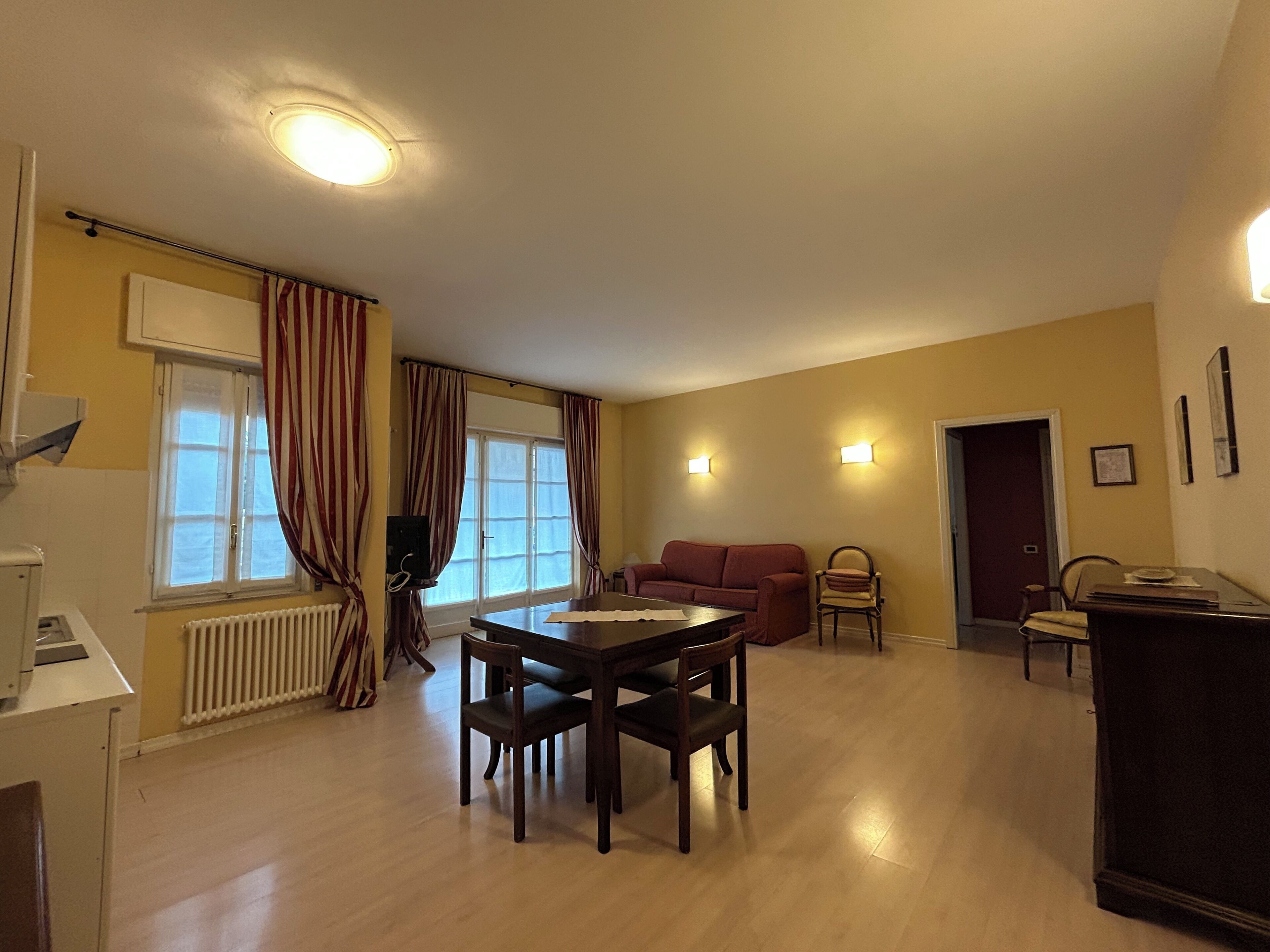 Een woonkamer met een eettafel, stoelen, een bank en een televisie.