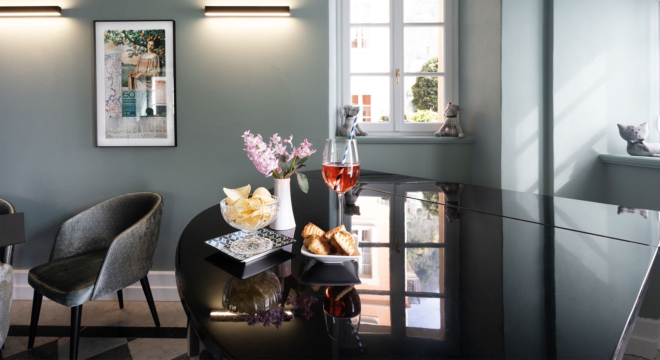 A cozy room with a chair, a table with snacks, a glass of drink, and a window with a view.