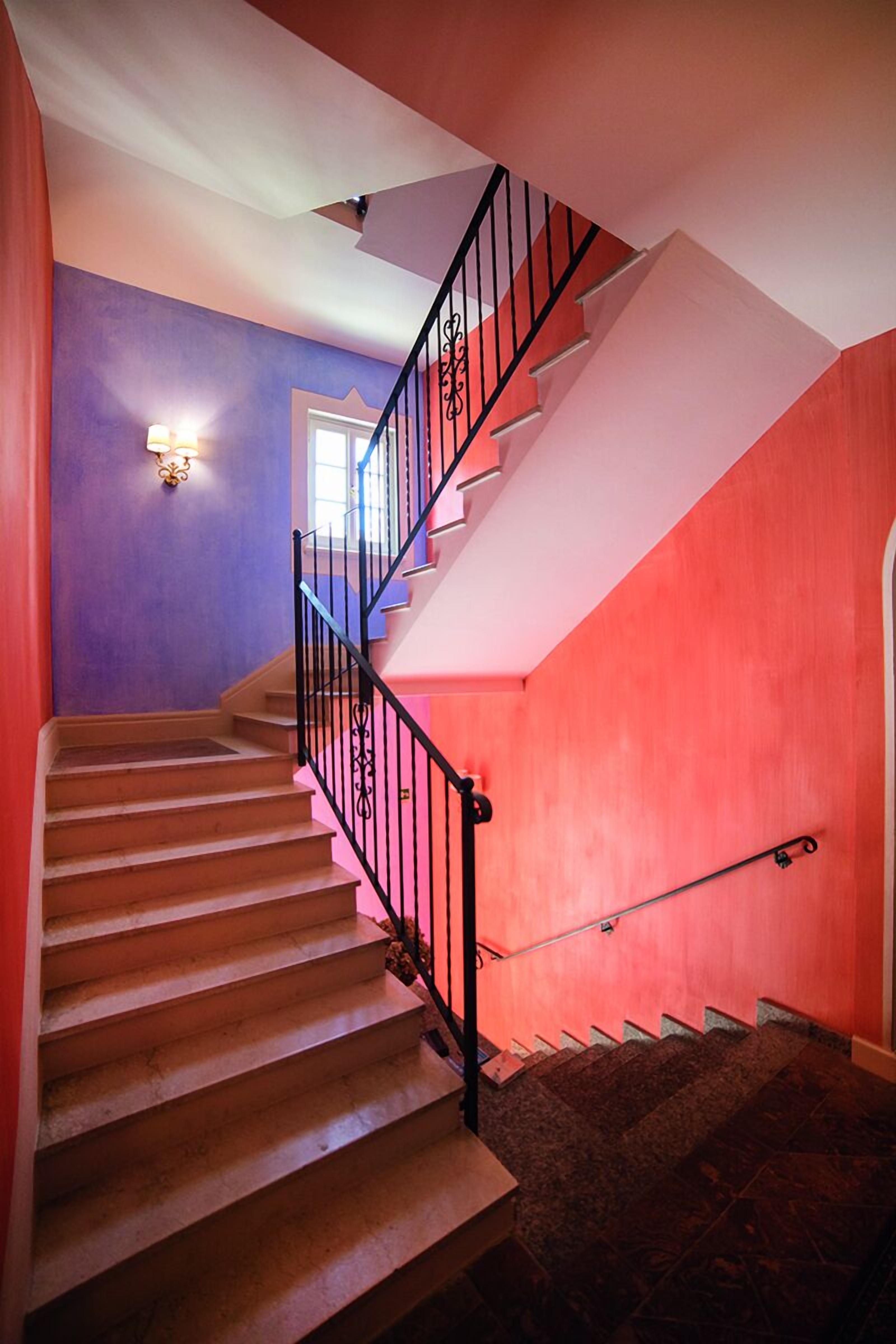 A staircase with a black railing, leading to a landing with a light fixture.