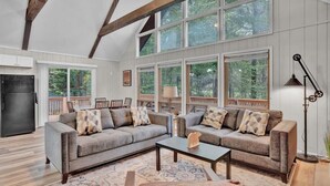 A spacious living room with two sofas, a coffee table, and a large window overlooking a deck.