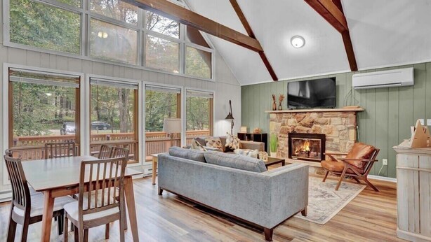 A spacious living room with a stone fireplace, large windows, and a cozy seating area.