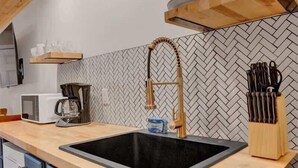 Eine moderne Küche mit einer Holz Arbeitsplatte, einem schwarzen Spülbecken und einer Rückwand mit Fischgrätmuster.