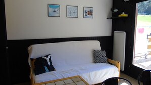 A room with a white sofa, two pillows, a small table, and three framed pictures on the wall. - Châtel Apartment 2 rooms - 4 people, near ski lift (Châtel)