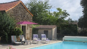 A stone building with a tiled roof, a swimming pool, and lounge chairs with umbrellas. - Gîte Dans Maison en Pierre, Avec Piscine, à la Campagne, Proche Villefranche (Savignac)