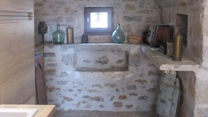 A rustic stone-walled kitchen with a small window, wooden cabinets, and a tiled floor. - Gîte Dans Maison en Pierre, Avec Piscine, à la Campagne, Proche Villefranche (Savignac)