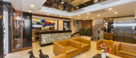 A modern lobby with leather sofas, a reception desk, and a large digital screen.