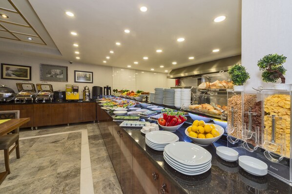 A buffet with various food items, including fruits, vegetables, and bread.
