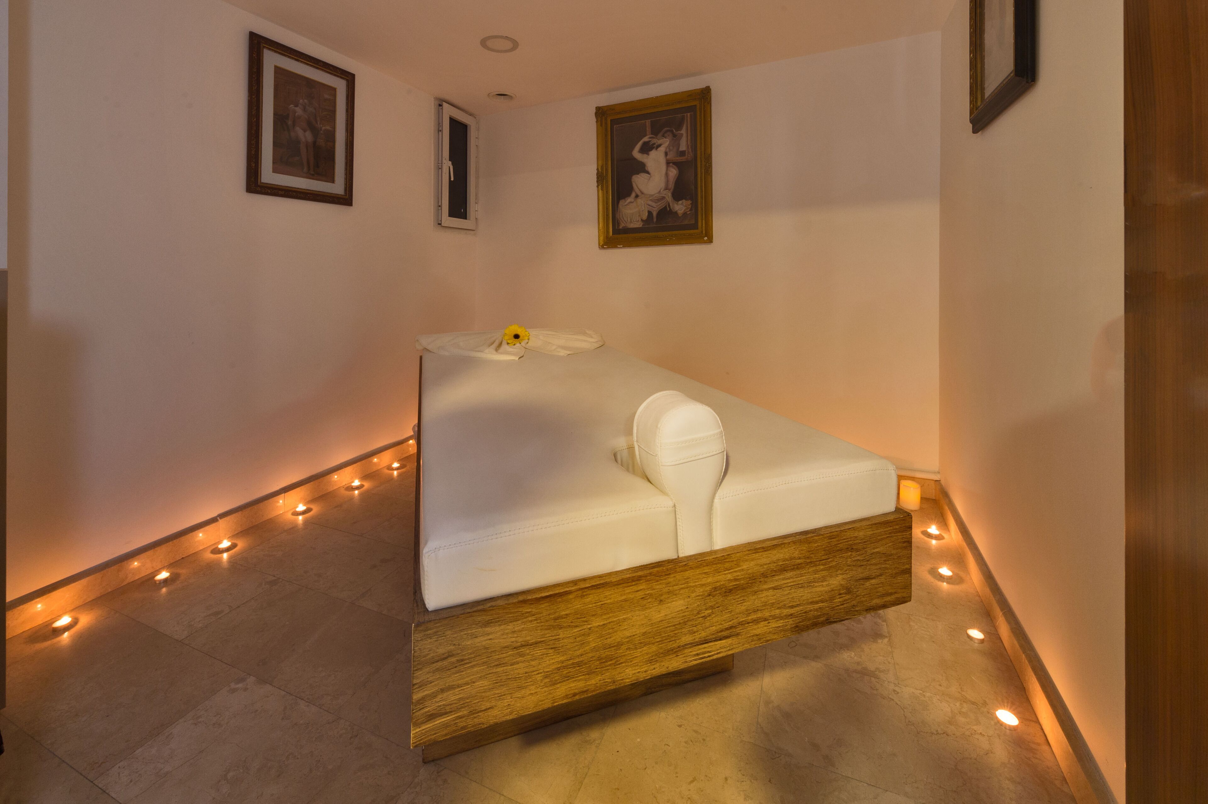 Une chambre à coucher moderne au design minimaliste, comprenant un lit avec un cadre en bois et un matelas blanc, une petite table de chevet et un cadre photo fixé au mur.